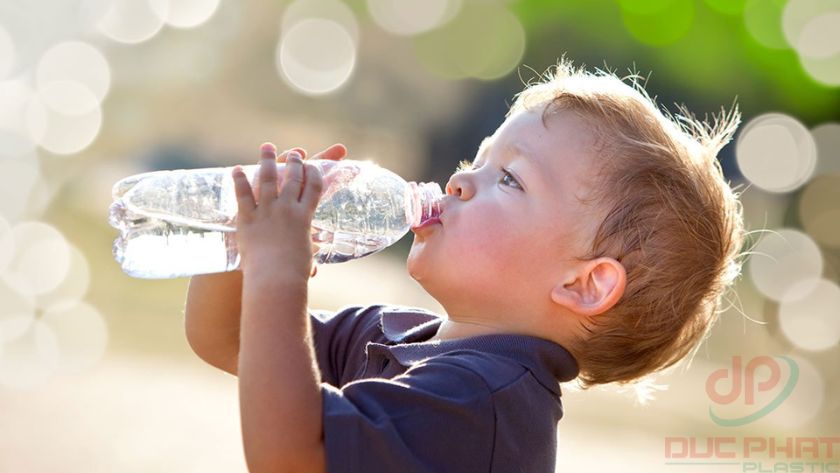 cách sử dụng nhựa PET an toàn: chỉ dùng một lần, không tái sử dụng lâu dài, tránh nhiệt cao và thực phẩm nóng Cậu bé cầm chai nước nhựa PET uống, minh họa nguyên tắc sử dụng an toàn: chỉ dùng một lần, tránh nhiệt cao, không đựng đồ nóng hoặc axit