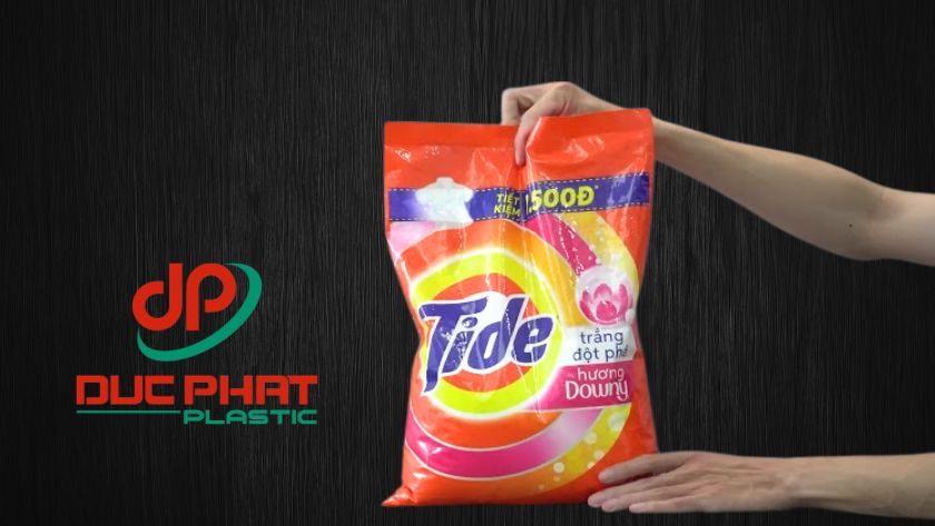 Bao bì bột giặt với 3 lớp: PET/OPP in sắc nét, AL/MPET rào cản tuyệt đối và PE/LLDPE hàn kín an toàn, tối ưu bảo quản và hiệu quả thương mại Bàn tay cầm bao bì bột giặt Tide, minh họa cấu trúc 3 lớp màng ghép: PET/OPP, AL/MPET và PE/LLDPE, giúp bảo vệ và kéo dài hạn sử dụng